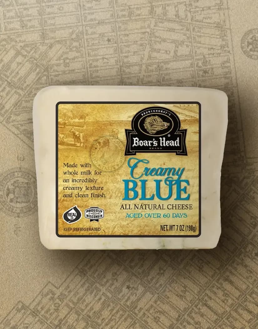 The Boar's Head® Creamy Blue Cheese sits on a tan illustrated image of New York City.