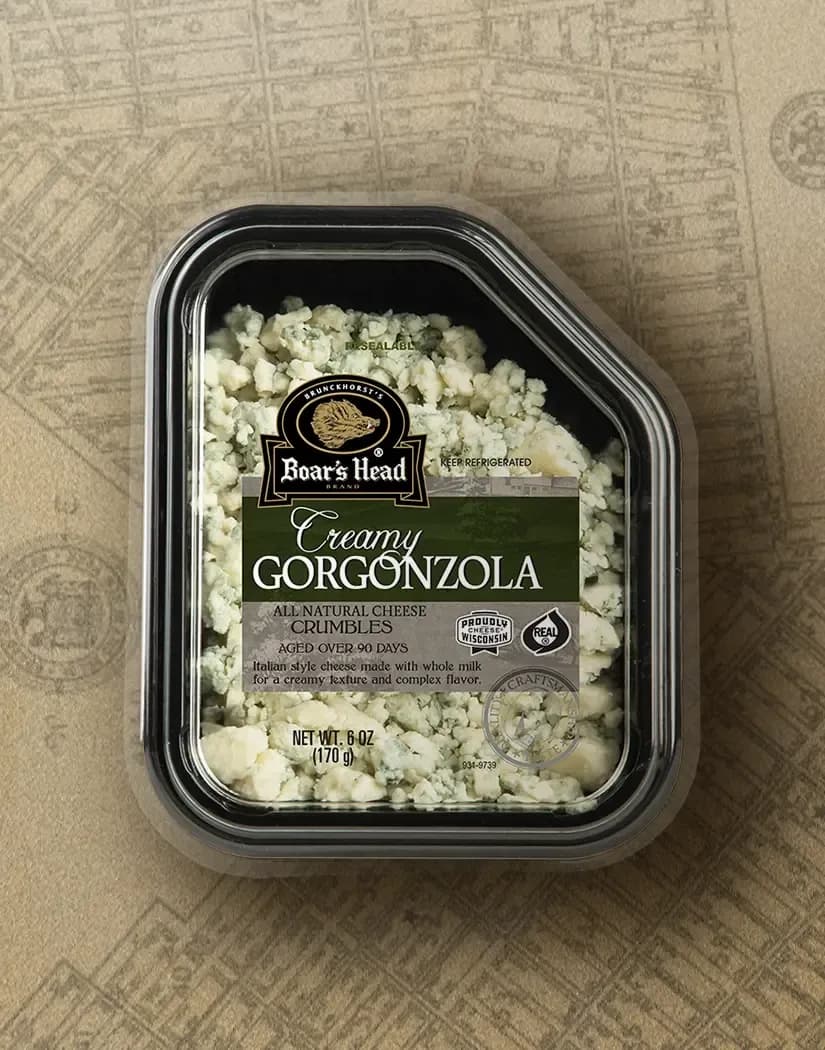 The Boar's Head® Creamy Gorgonzola Cheese Crumbles sits on a tan illustrated image of New York City.