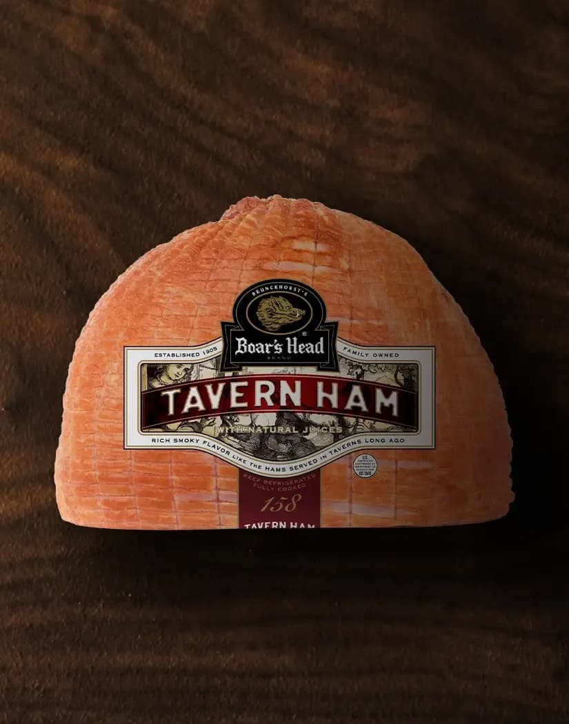 A aerial view of a package of the Boar's Head® Tavern Ham sitting on a wood grain background.